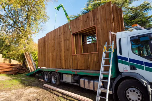 Holzhaus-Bauen-4 Fertighauselemente aus Holz auf einem Lastkraftwagen.